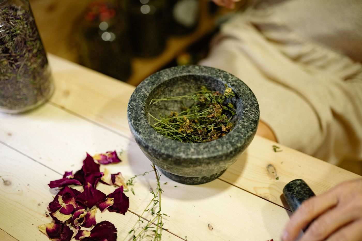 Dried herbs being prepared in a stone mortar and pestle